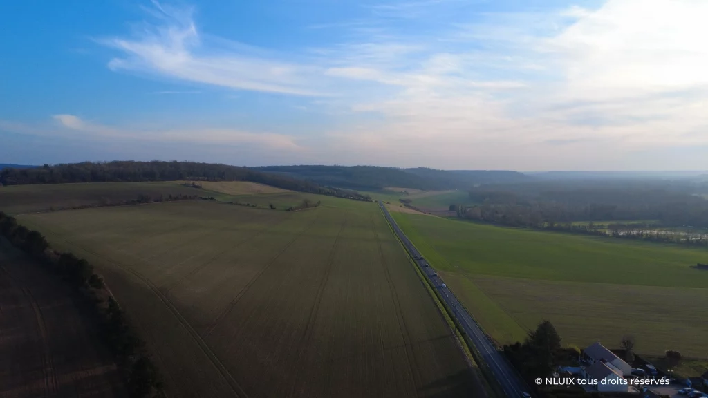 Photo aérienne du paysage du Vexin, entre deux champs, une route qui pointe vers l'horizon vallonné.