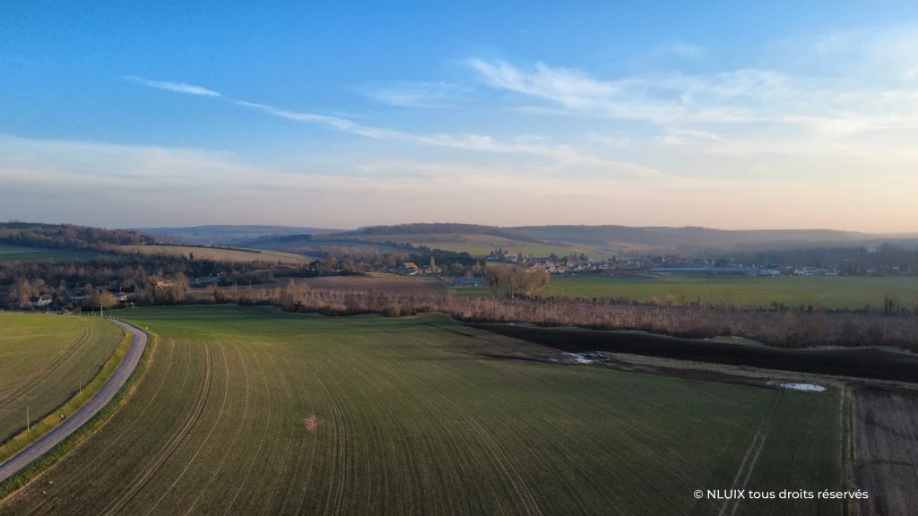 Paysage vallonné au soleil couchant, des champs, des forêts, des habitations dans le Vexin