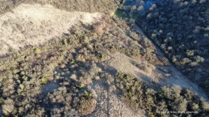Photo plongeante sur un zone vallonnée composée de roche et d'arbres.
